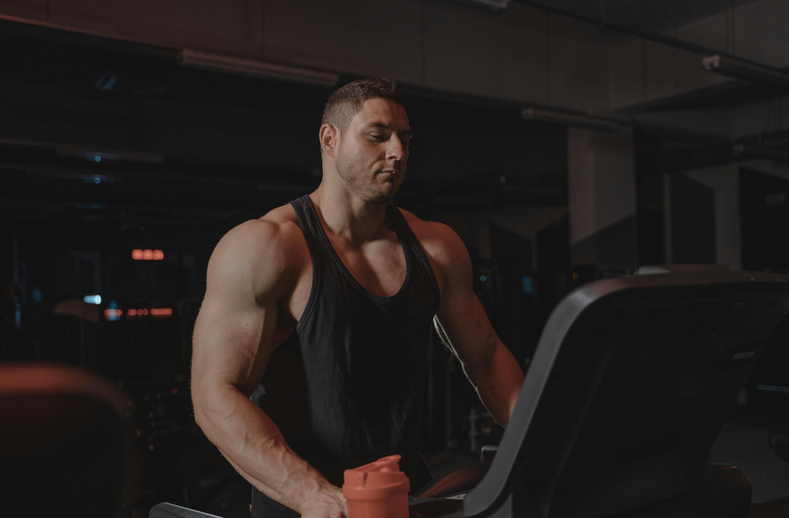 A bodybuilder working out on a treadmill at the gym, focused on fitness and strength training.