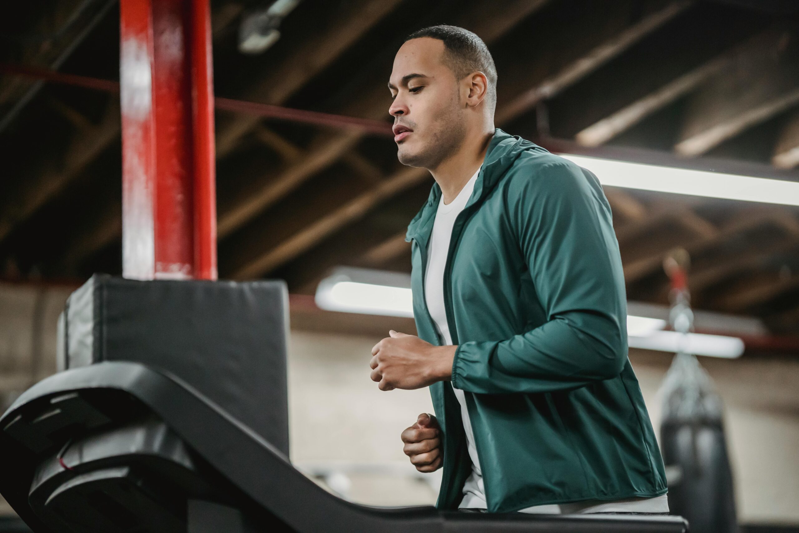 An athletic man in activewear running on a treadmill indoors, focused on fitness and health.