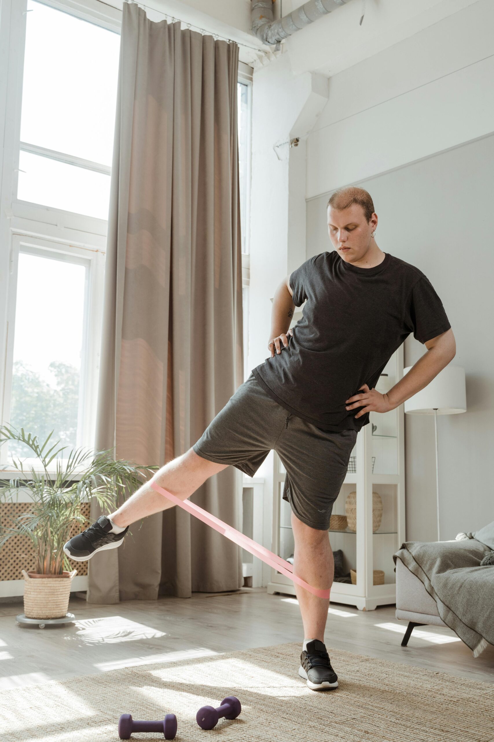 Man exercising with resistance band in a bright home living room.
