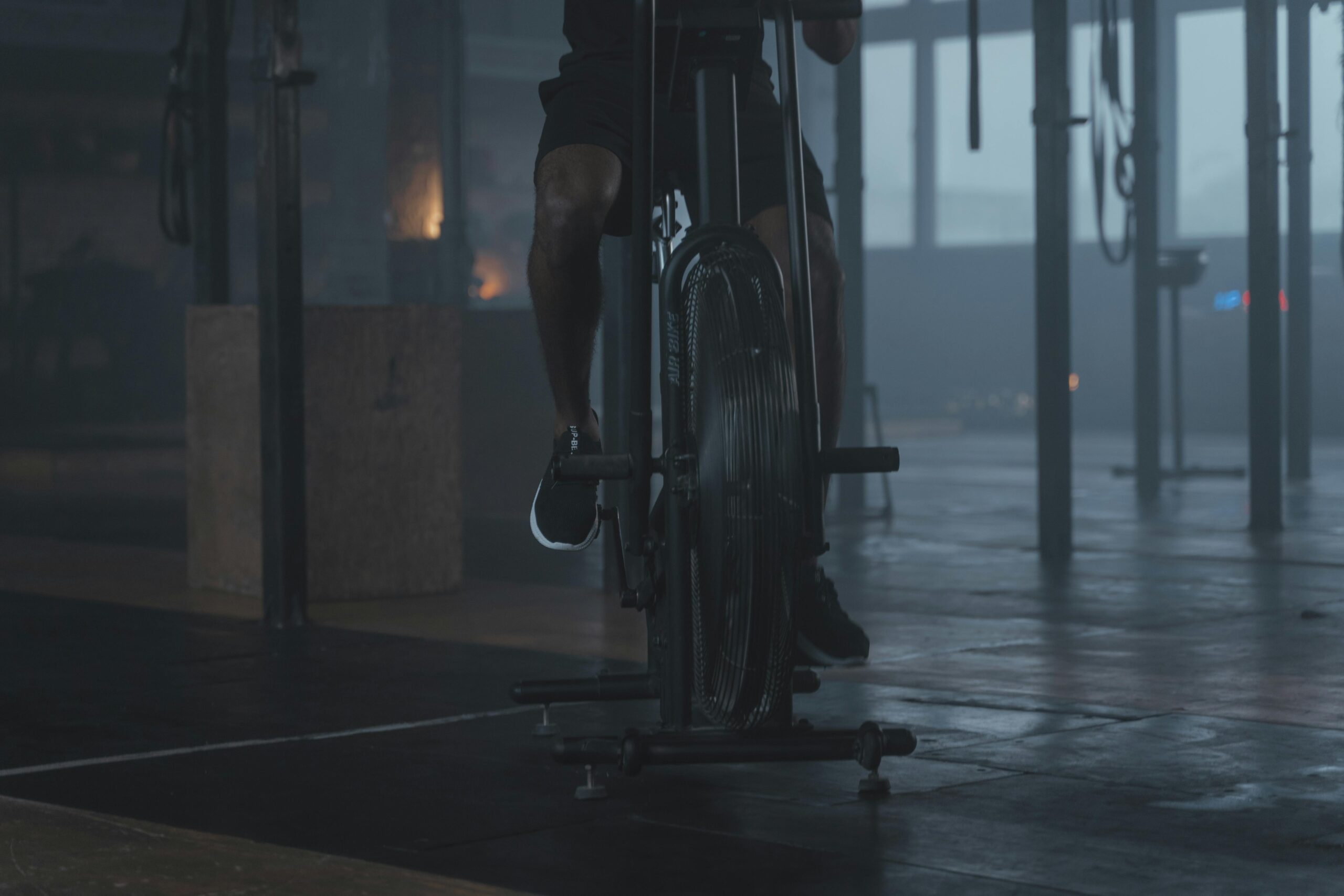 Close-up of a person exercising on a stationary bike in a dimly lit gym setting.